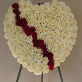 Heart-shaped rose arrangement with a red diagonal stripe on an easel