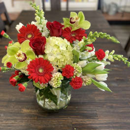Red and green mixed flower arrangement in a glass vase