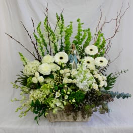 White floral arrangement in a wicker basket with a small statue at center