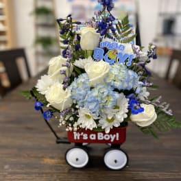 Blue and white flower arrangement in a wagon with an "It's a Boy!" sign