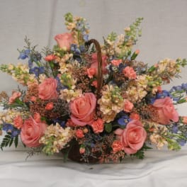 Basket arrangement of pink roses and blue flowers