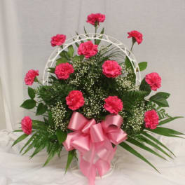 Pink carnations in a white basket with a pink ribbon