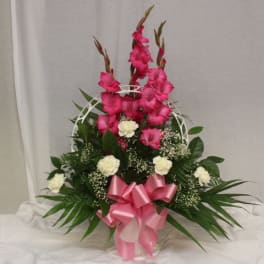 Pink gladiolus arrangement with white carnations in a basket and pink ribbon