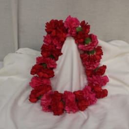 Red and pink carnation lei draped over white fabric