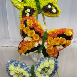 Butterfly-shaped floral display on an easel in yellow, orange, blue, and white.