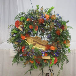 Large floral wreath on a stand with orange, purple, and green blooms