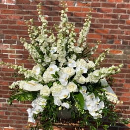 Large white floral arrangement with orchids and roses in a basket