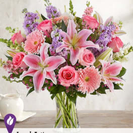 Pink lilies, roses, and gerbera daisies in a clear glass vase