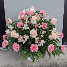 Pink roses and carnations arranged in a white basket.