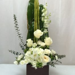 Tall white floral arrangement in a dark square vase