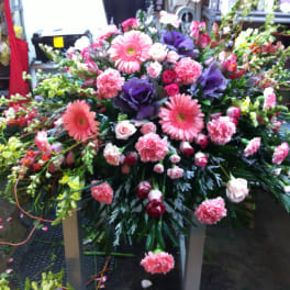 Large mixed floral spray with pink and purple blooms on a stand