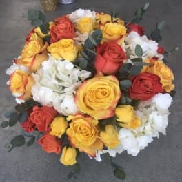 Round bouquet of red, yellow, and white roses with eucalyptus