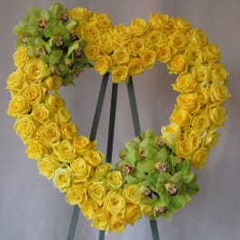 Heart-shaped wreath of yellow roses with green orchids on an easel