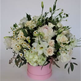 White and blush floral arrangement in a pink round box