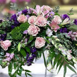 Low floral casket spray with pink roses and purple flowers