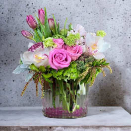 Pink roses and tulips arranged in a clear glass vase