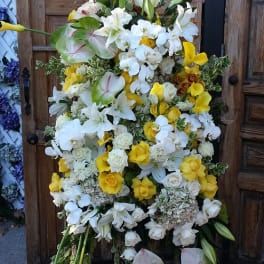 Large standing floral spray with white lilies, orchids, roses, and yellow calla lilies