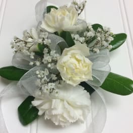 White floral corsage with ribbon and green leaves