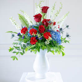 Red roses and blue hydrangeas in a white vase