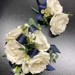 White rose corsages with navy ribbon and small white filler flowers