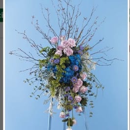 Tall floral arrangement with pink and blue flowers on a stand