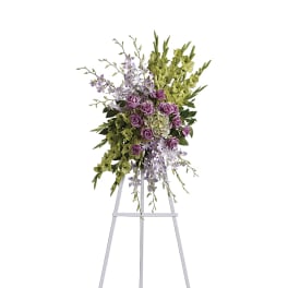 Standing floral spray with purple roses and green gladiolus on an easel
