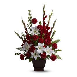 Red carnations and white lilies in a dark urn vase