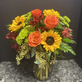 Bouquet of orange roses and yellow sunflowers in a glass vase