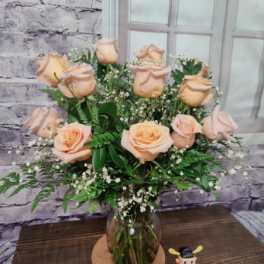 Peach roses arranged in a glass vase with baby's breath