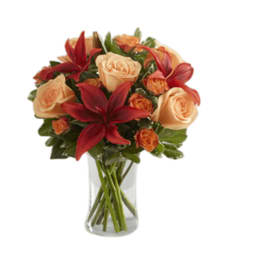 Bouquet of peach roses and red lilies in a clear glass vase
