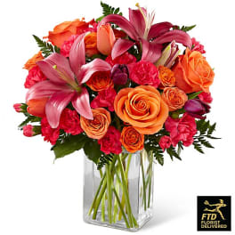 Bouquet of orange roses and pink lilies in a clear glass vase