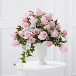 Pink roses and carnations arranged in a white vase