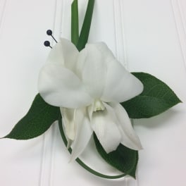 White orchid corsage with green leaves and black berry accents