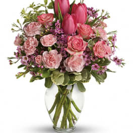 Pink tulips and roses arranged in a clear glass vase