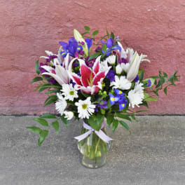 Bouquet of lilies, irises, and white daisies in a glass vase
