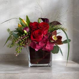Red roses and pink orchids in a square glass vase