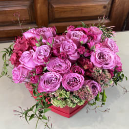 Pink rose arrangement in a red box with small accent flowers