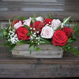 Red and pale pink roses arranged in a wooden box