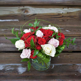 Bouquet of red, white, and pale pink roses in a glass vase