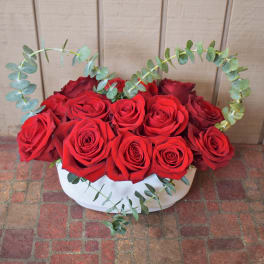Red roses arranged in a white box with heart-shaped eucalyptus stems