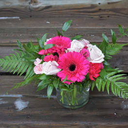 Pink gerbera daisies and roses in a glass vase