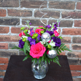 Bright pink and purple flower arrangement in a glass vase with disco balls