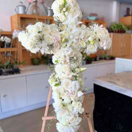 White floral cross arrangement on a wooden easel