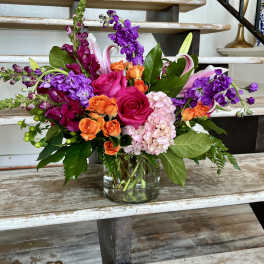 Mixed bouquet of pink, orange, and purple flowers in a glass vase