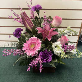 Pink and purple floral arrangement in a low container
