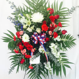 Large standing floral spray with red, white, and blue flowers on an easel
