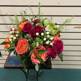 Bouquet of pink and orange roses with green orchids in a vase