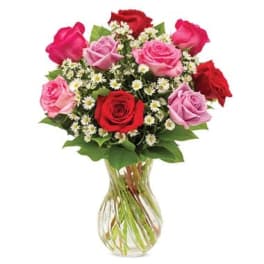 Bouquet of red, pink, and lavender roses in a clear glass vase