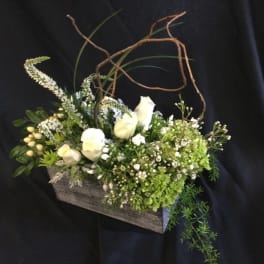 White flowers and green blooms arranged in a rustic wooden box