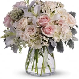 Blush roses and white lilies in a clear glass vase